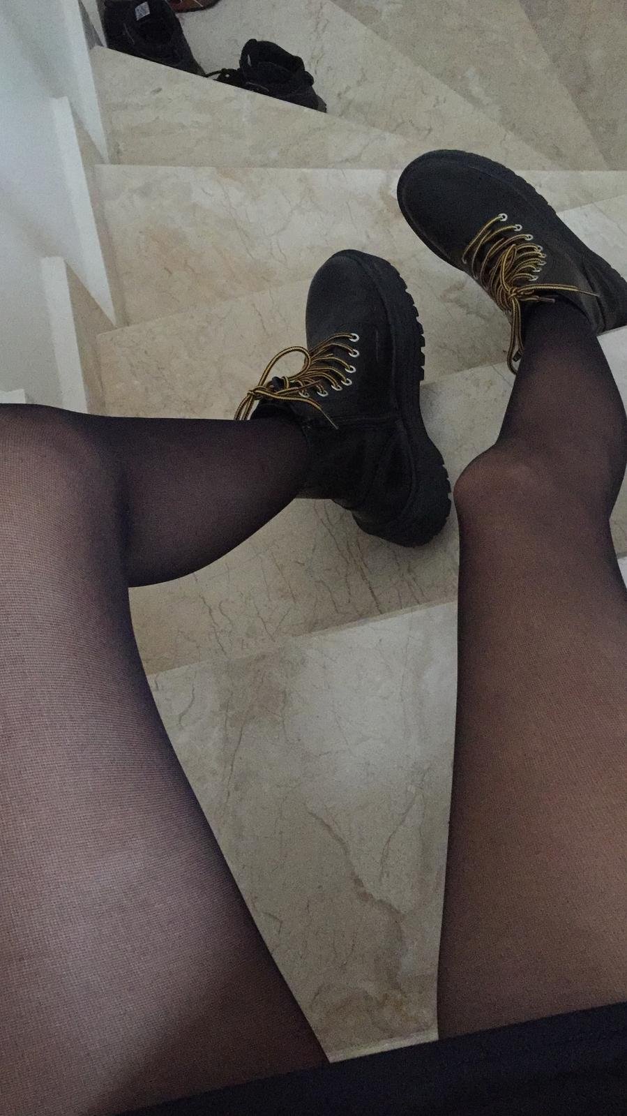 Legs in black stockings and boots on stairs
