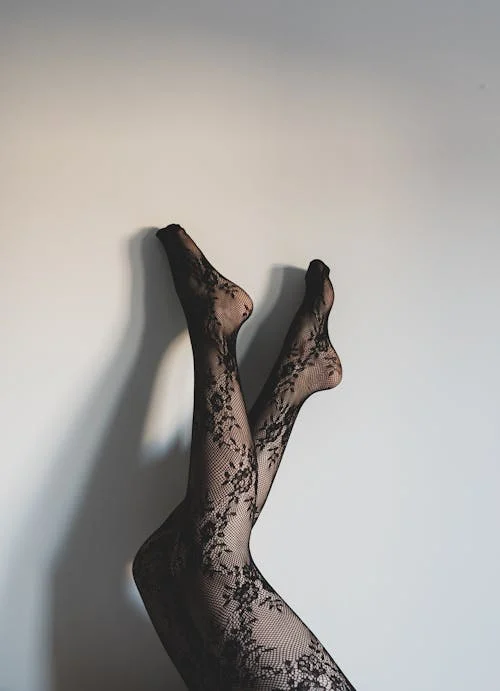 Legs in black lace stockings against wall