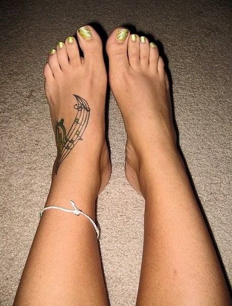 Feet with gold nail polish and music note tattoo